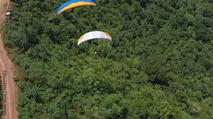 Amazing aerial video of flying paraglider on the background of wild nature. Paraplan drifting above the green tropical trees. Extreme sport. Hipster modern hobby concept. Paraplane flying in the sky.