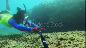 selfie of side view of an asian female free diver wearing bikini wet suit and snorkel mask looking to find stuff underneath massive coral with dead coral fraction with no creatures fishes