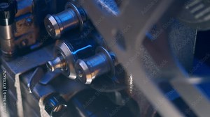 Close-up of vintage 16mm film projector reels under blue light, playing old film on mid-20th century tech. Spinning silver reels of retro film opener.