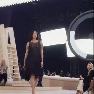 Mixing precious textures, a short flared dress in black organza is embroidered with a gradient of black feathers, fringes and glittering beads. The CHANEL Spring-Summer 2022 Haute Couture collection. Cristal Baschet © ADAGP Paris 2022 See all the looks at chanel.com/-HC_SS22 | CHANEL