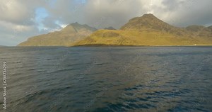 Flying low over water towards the Cuillin mountains on the Isle of Skye, Scotland. Stock Video