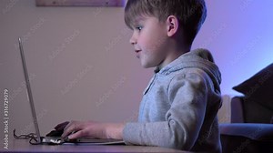 Child playing video games and using computer. Boy is Focused Looking At Computer Screen. Futuristic rgb backlights