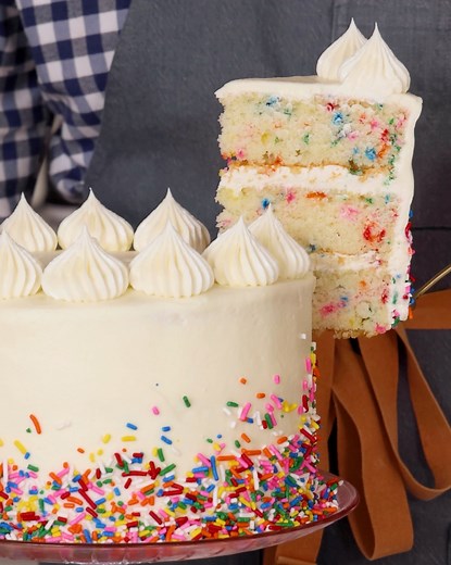 This colorful Funfetti Cake is as delicious as it is festive! Tall layers of moist, soft white cake dotted liberally with rainbow sprinkles are smothered in a fluffy buttercream. Perfect for birthdays or any special occasion! | Preppy Kitchen