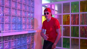 Funny break dancer moving freestyle step to hiphop while looking at camera. Crazy happy hipster dancing and performing street dancing while wear casual outfit and sunglasses in Led light. Regalement.