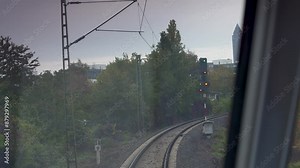 Driver's view from a train, capturing curved tracks and a green light ahead in an urban setting