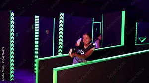 Girls play laser tag, jokingly fight with light weapons, hide behind obstacle. Laser tag participants hide from enemy, support course of game