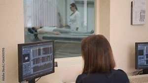 Doctor looking at computer screen while patient moving in mri machine. 4k