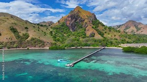 Paradise drone view of Komodo island national park in Indonesia, white luxury yacht in turquoise ocean with coral reefs at a secluded beach, adventure tropical cruise