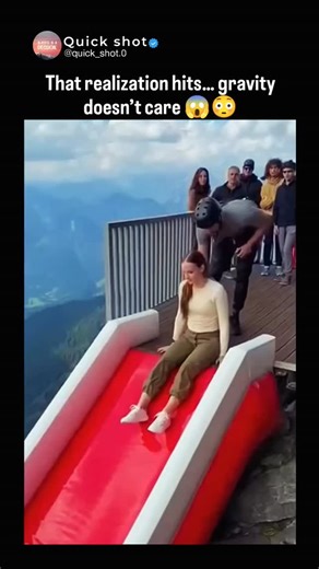 Quickshot on Instagram: "Dm for credit and removel The post features a 10-second clip showing a woman and an instructor sliding down a bright red inflatable ramp built along a Swiss Alps cliff, dropping roughly 100 feet into a large blue suspended airbag that launches them back upward on impact. The dramatic visuals sparked 182 replies from Indonesian viewers, many expressing fear and questioning whether the footage was real. The attraction is actually a bigairbag® installation, designed for yea