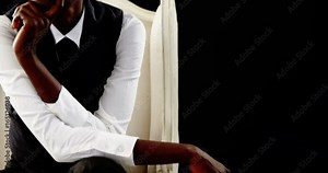 Androgynous man posing on armchair against black background