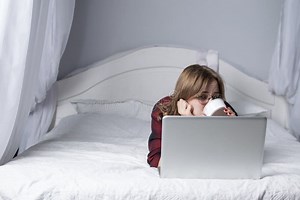 Girl is Lying in Bed with a Laptop and Watching a Video with Coffee, Female Freelancer Works at Home, she Uses a Computer and Stock Image - Image of beauty, person: 155005439