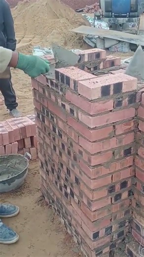 installing bricks to make pillars in a house that is being built. with cement too