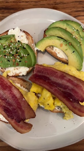 open faced breakfast sandwich with whipped cream cheese, scrambled eggs, bacon, avocado, everything seasoning a drizzle of hot honey 🤌