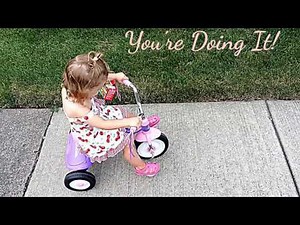 A toddler is learning how to ride a tricycle!