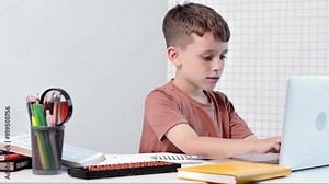 School kid with computer having video conference chat with teacher and class group. Child studying from home. Homeschooling. Modern gadgets for education. Screen time control. Online remote learning