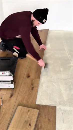 man is installing wooden laminate flooring planks carefully on a prepared surface
