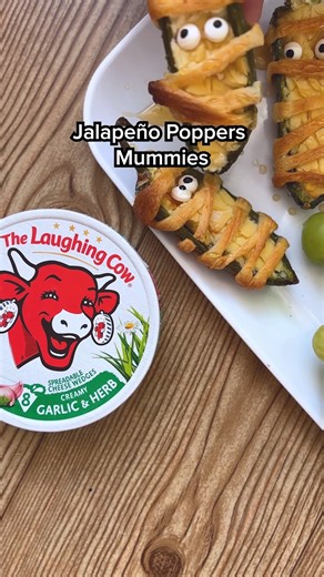 Warning: these cheesy mummies are scary delicious 👀 Ingredients: -10 fresh jalapeños -10 wedges of The Laughing Cow cheese (Garlic & Herb or Aged White Cheddar are great options) -1 tube of crescent roll dough - Candy eyes - Hot honey (optional) Directions: -Preheat oven to 400°F. -Slice each jalapeño in half lengthwise and scoop out seeds. -Spread a wedge of The Laughing Cow cheese inside each jalapeño half. -Unroll the crescent dough and cut into thin strips (about ¼ inch wide). -Wrap each ja