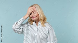 Shocked elderly gray-haired blonde woman lady 40s years old wears white shirt put hand on face facepalm epic fail mistaken omg gesture isolated on plain pastel light blue background studio portrait