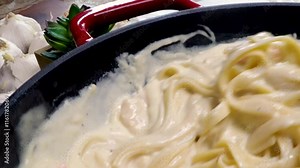 Making shrimp fettuccine alfredo with for a meal. Cooking a seafood pasta dish with cheesy alfredo sauce with pasta noodles and shrimp.