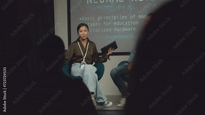 Full selective focus shot of Caucasian male speaker and Asian female moderator sitting together on stage at IT conference, finishing presentation, and audience clapping