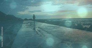 Person jogging on wet pathway by ocean, with light effects animation