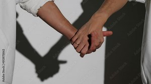 Female hands join in a handshake, close-up, white background.On one hand is an engagement ring