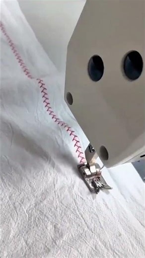 sewing a red zigzag pattern on a white fabric precisely using an industrial machine in a workshop