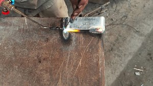 closeup of Welders hand doing gas weld with sparks flying as metal is being on a workbench at workshop asia