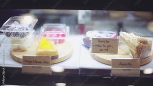 Shop window in a bakery or grocery shop with wide choice or range of various deserts with beautiful blurred bokeh on background. 1920x1080