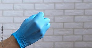 Angry middle finger. A view of stressed doctor show the middle finger in rubber blue glove in the room.