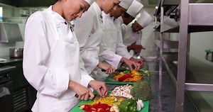 clip-5942483-portrait-team-multi-ethnic-chefs-slicing-vegetables-commercial