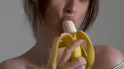 Close up female mouth eating peeled banana