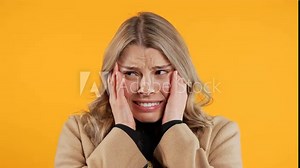Woman afraid of something, she in shock on yellow backdrop.Shut mouth, screaming