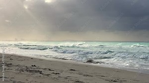 A beautiful Cuban beach in Varadero, Cuba, where you can see the waves and ocean waters on a cloudy day with the sun breaking through the clouds. Turquoise waves. 4K Video