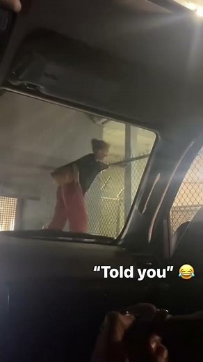 Woman is trying to jump over a fence and falls off the trash cans that she's standing on!
