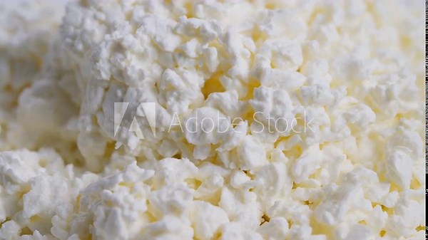 Texture of soft cottage cheese granules, Macro view highlighting grainy cottage cheese texture, Closeup image showcasing creamy cottage cheese curds packed in bowl