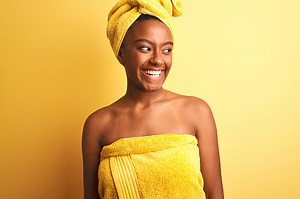 African american woman wearing towel after shower standing over...