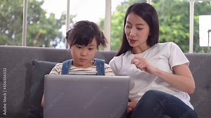 Mother is teaching her daughter to use the Laptop to surf the Internet and making online communication at home.