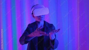 Young guy a professional gamer in virtual reality glasses. Immersed in a parallel reality, creates architectural objects. Futuristic white VR glasses. The designer creates new art.