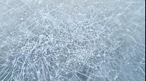 Intricate frost patterns and cracks on a frozen surface, showcasing winter cold