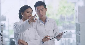 Two scientists using a digital tablet while brainstorming equations and formulas on a glass wall in a lab. Forensic pathologists analyzing data and research. Clinical researchers developing a theory