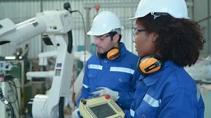 Young female engineers trainee are doing apprenticeships and learning from seniors who give advice. operation of robotic welding machine