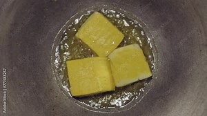 the process of cooking tofu by frying the tofu until it turns almost golden yellow