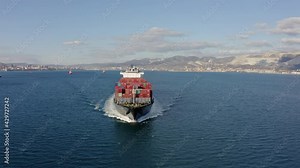 Ultra large loaded container ship cruising in open ocean, aerial view. High quality drone footage of Cargo ship departing from the port. Concept of freight transportation, import export business