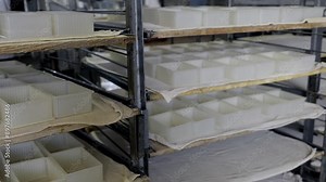 White Plastic Containers On Wooden Shelves At Cheese Manufacturing Automated Factory. Cottage Cheese And Milk Automated Production. Automated Processes At Plant. Food Industry. Panoramic Shot.