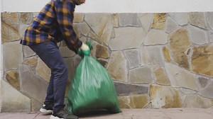 Caucasian male picking up heavy garbage trash bag filled with Biological Food Waste, Recyclable Bottles Garbage | Premium Stock Video Footage