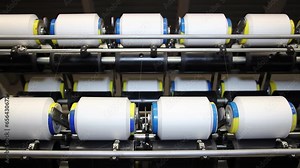 Thread Manufacturing in Textile Industry. Spools With Threads Spinning at Textile Factory. Yarn is produced by spinning raw fibers of cotton or other materials to produce long strands.