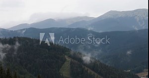 Beautiful landscape of mountains with green wild forest and clouds in sky during rainy weather. Natural backdrop and wallpaper.