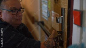 A woman with missing hands opens the door lock of the house.