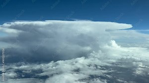 Pilot POV FPV flying in a turbulent sky with a massive and dangerous cumulonimbus storm cloud. Aerial footage taken from the cockpit of a jet flying at cruise level. Daylight, blue sky. 4K 60FPS